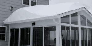 White aluminum three-season sunroom covered in snow, showing energy-efficient WeatherMaster™ windows.