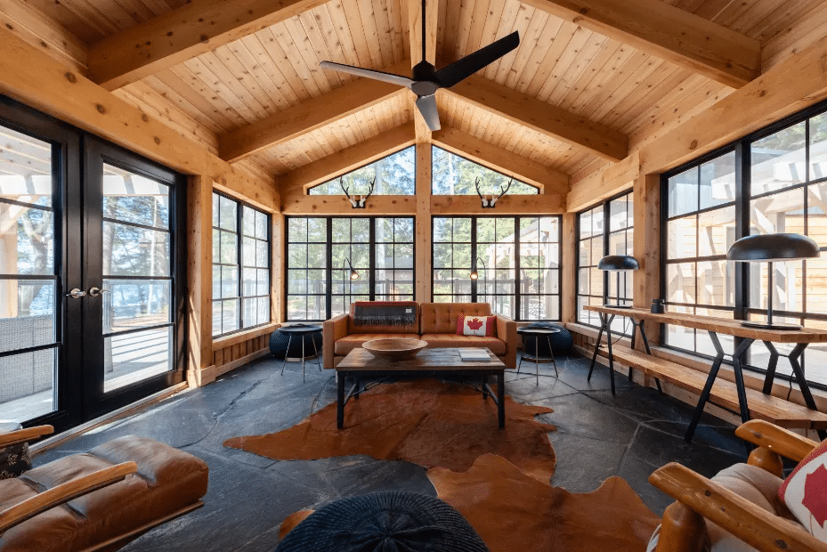 Room with wood ceiling, windows, and stone floor