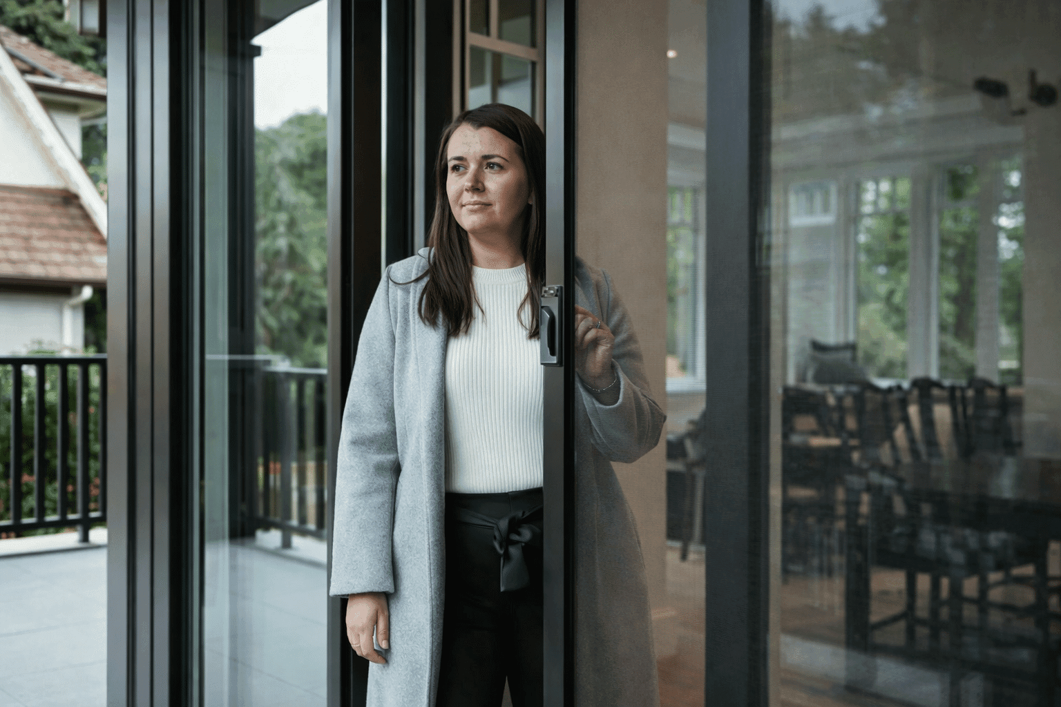 Woman standing next to a sliding glass door indoors